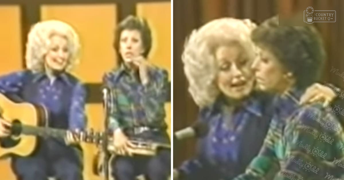 Indoor musical performance scene with two adult females; one in blue denim jacket and another in green plaid shirt, both holding guitars against plain yellowish walls under artificial lighting.
