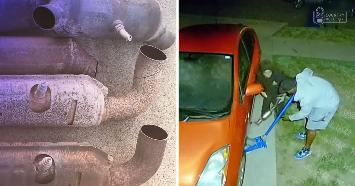 Rusty exhaust pipes in a residential outdoor setting with an orange car and dim lighting at night.