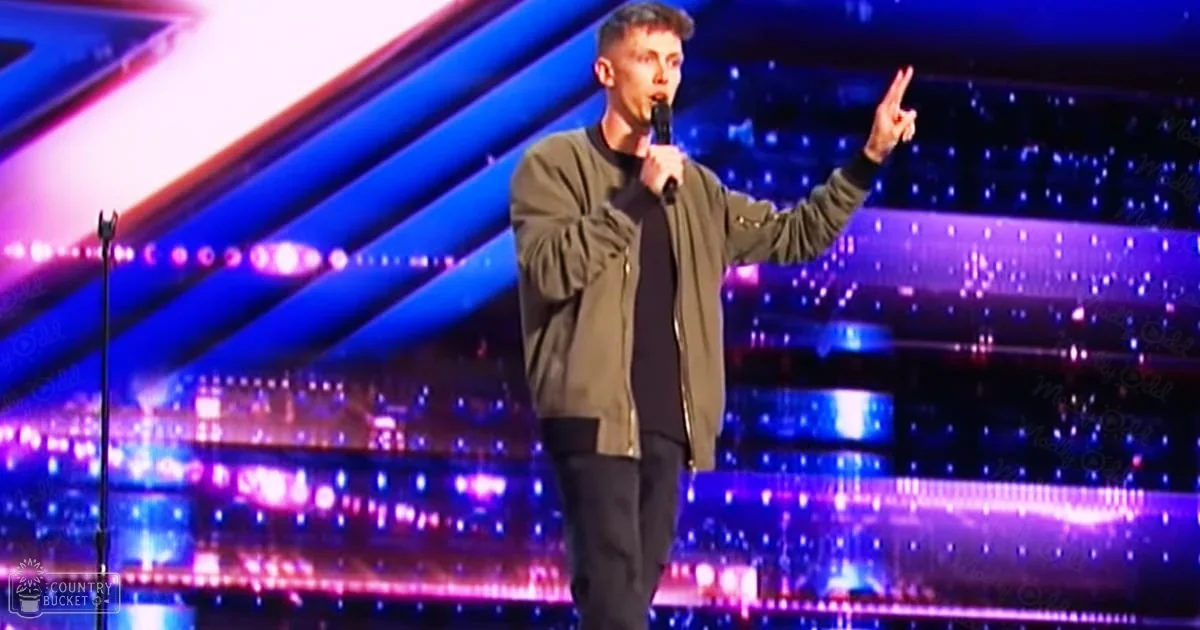A young adult male performs on stage at a talent show with vibrant lighting and an audience in the background.