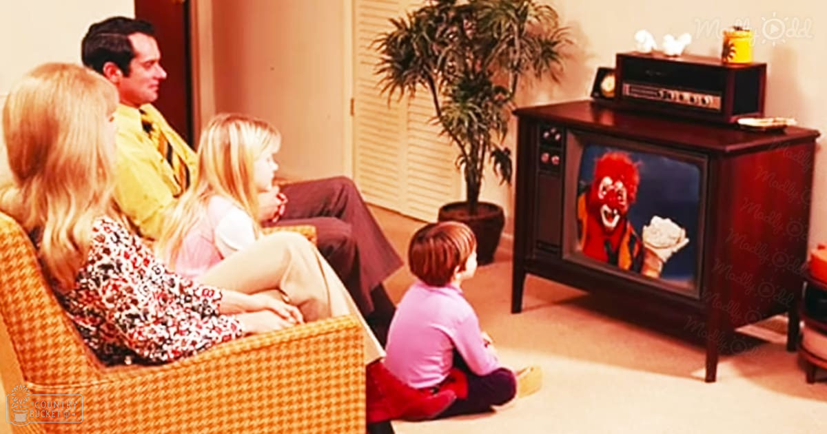 A family in their living room, with adults wearing 1970s-style clothing and a child on the woman's lap, surrounded by vintage furniture and decor.