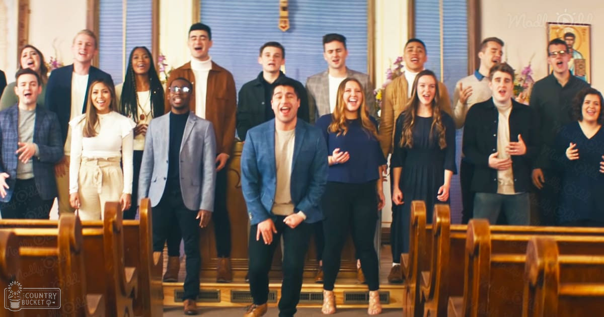 A group of young adults in a church setting with light-colored walls and blue window blinds.