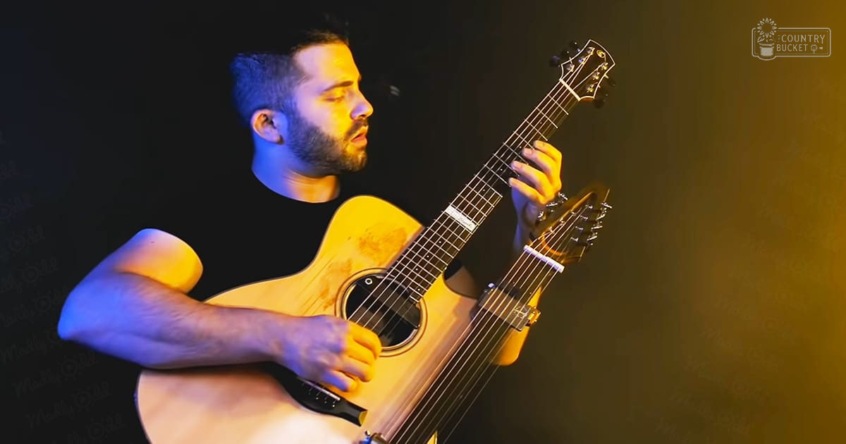 Adult male musician playing an acoustic guitar in a performance setting with 'Madly Odd' watermark.