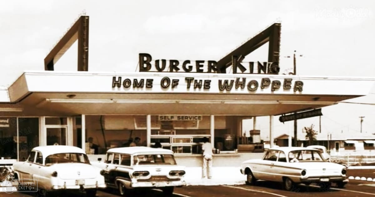 Vintage cars parked outside Burger King restaurant on urban street under overcast sky