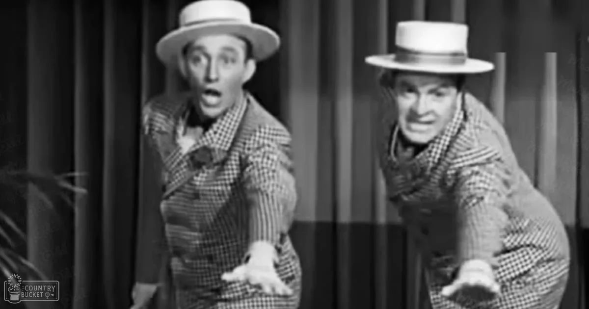 Two adult male singers dressed in matching black and white checkered suit jackets with bow ties, standing on a stage with theatrical lighting.