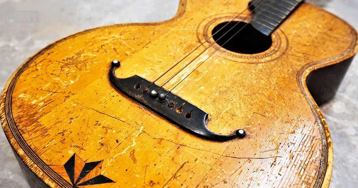 An old guitar in a studio setting with even bright lighting.