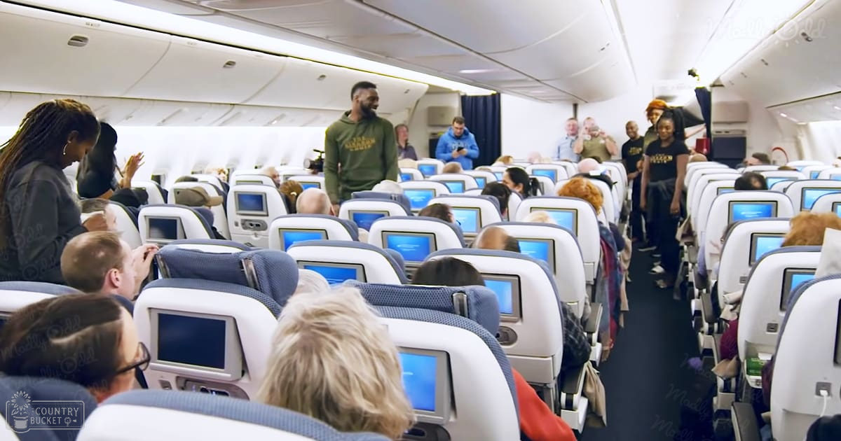 Passengers inside an airplane cabin with seats and entertainment screens during daytime.