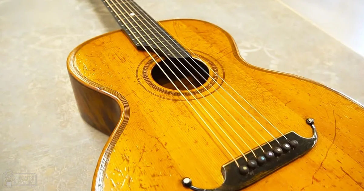 A classical guitar with a wooden body and six strings indoors on a light surface or tablecloth.