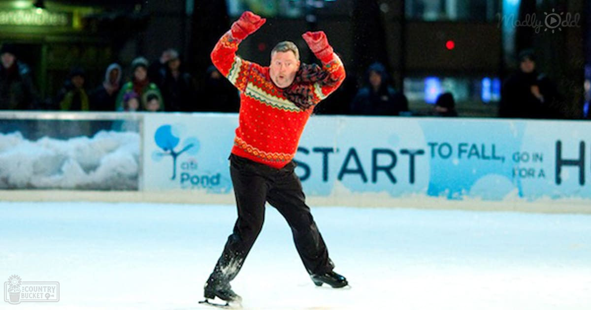 An adult male skating in a festive red sweater at an outdoor ice rink with winter season and evening light.