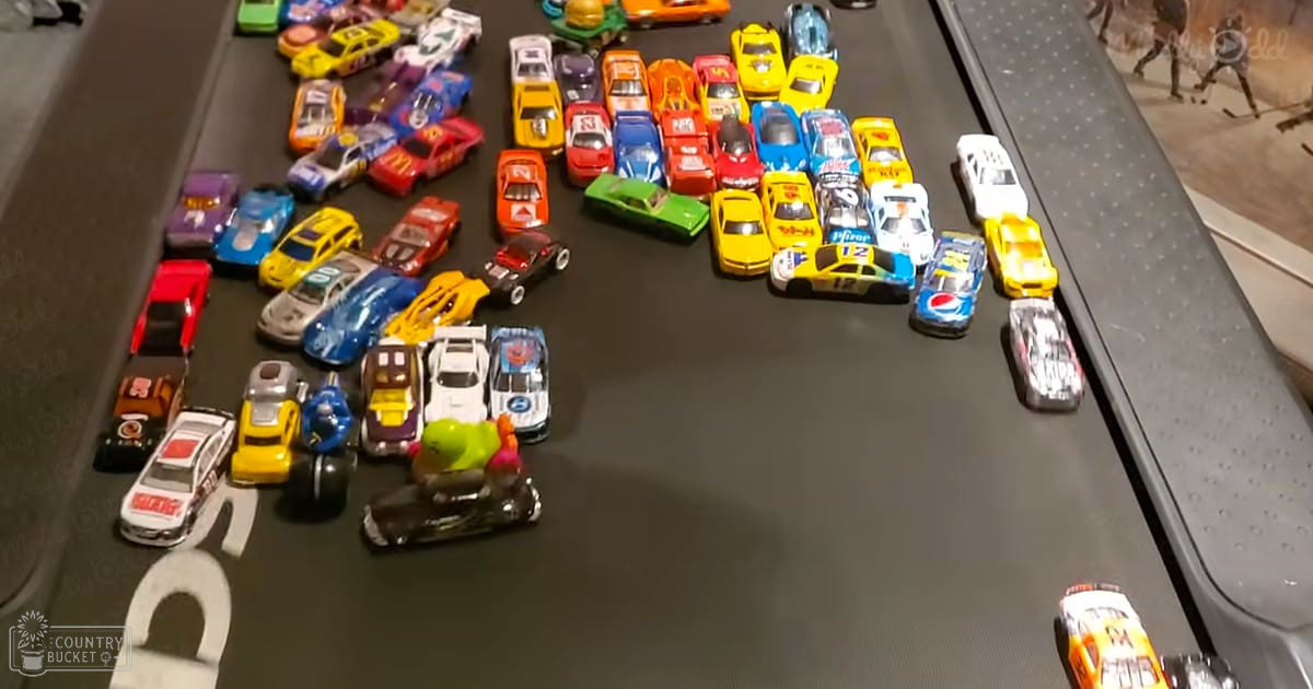 Indoor scene with toy cars arranged on a dark surface; various colors of toy vehicles dominate, including logos like 'Pepsi' and 'Dodge'.