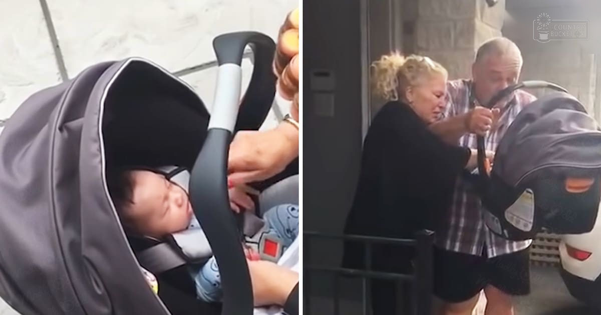 A baby in a stroller outdoors near an urban building with adults adjusting the stroller, under natural daylight.