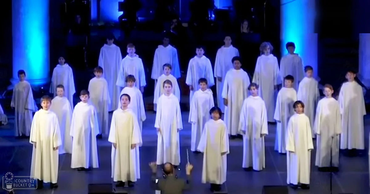 Children performing in a choir in an indoor performance space with blue stage lighting.