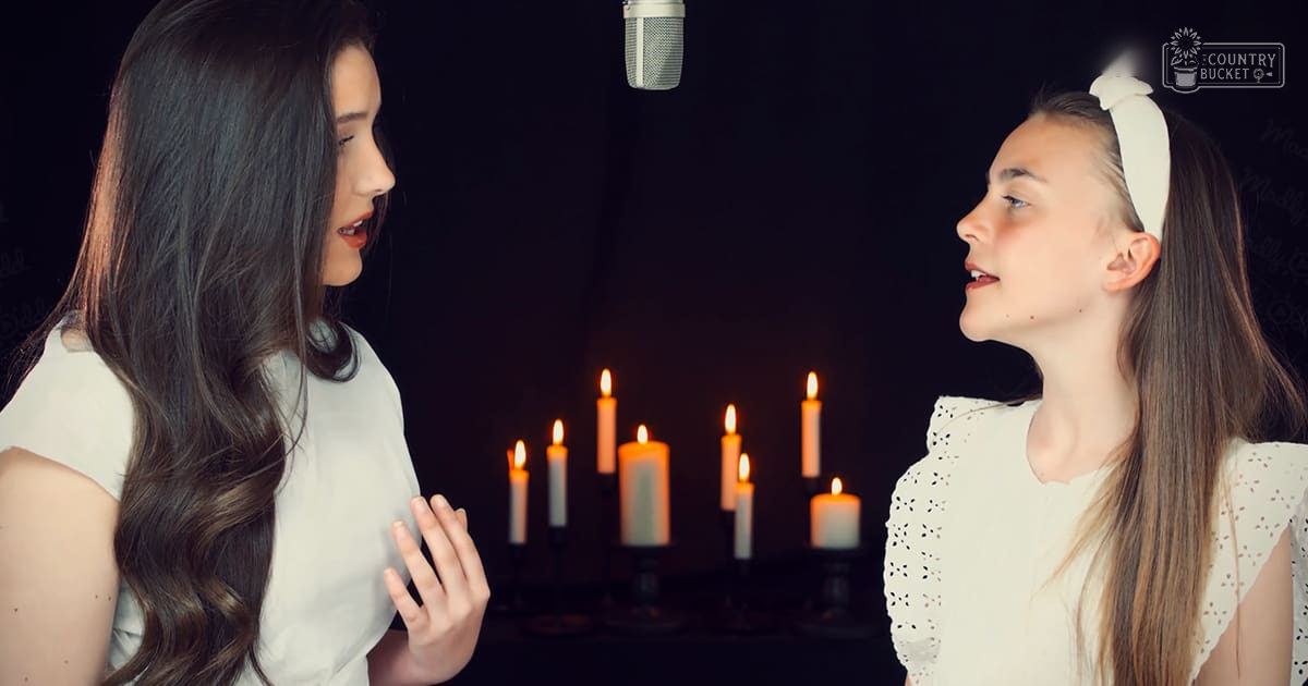 Two young adults singing in a studio setting with microphones and lit candles, dark studio environment.
