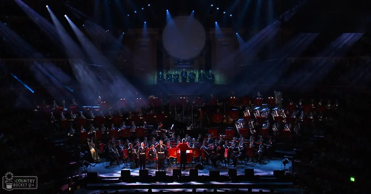 A group of adults in ceremonial dress uniforms perform on stage inside a concert hall.