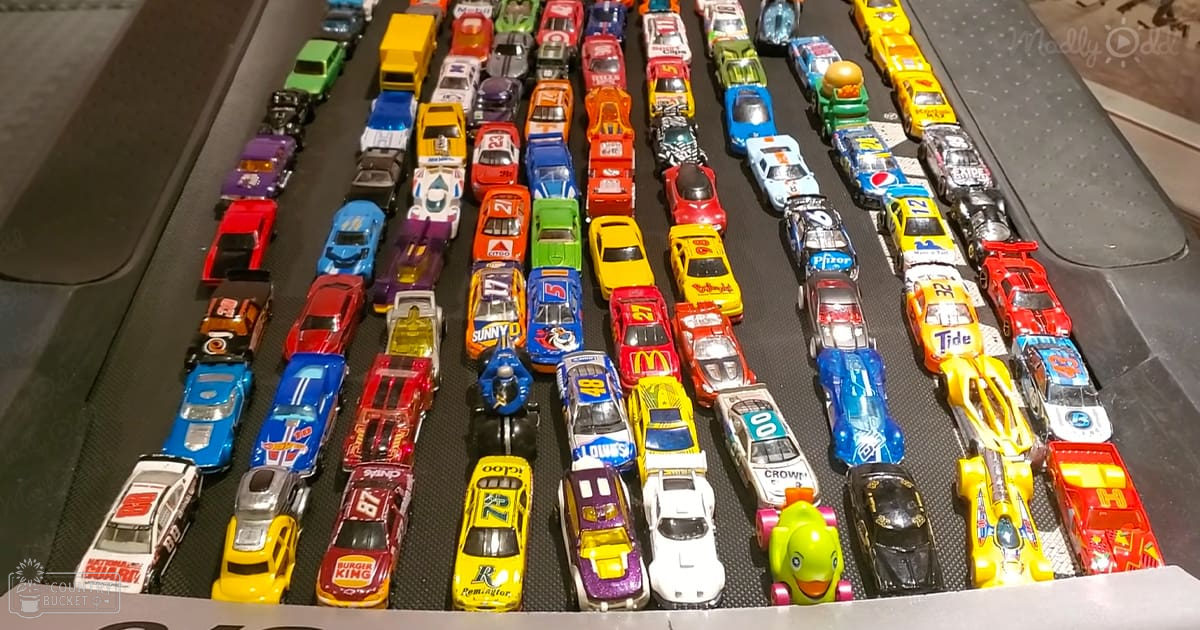 Assorted colorful toy cars displayed in an indoor collector’s showcase with artificial lighting.