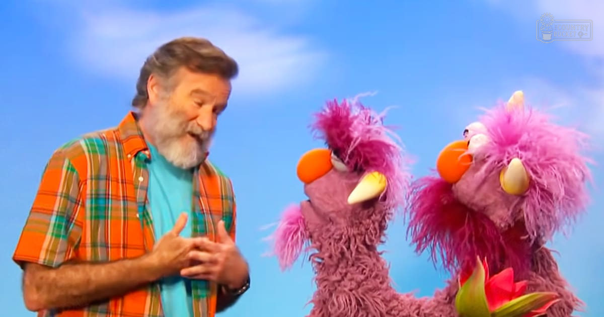 Two pink muppet characters resembling birds or monsters hold a red flower against a bright blue sky with white clouds, suggesting an outdoor setting. The scene is vibrant and playful.