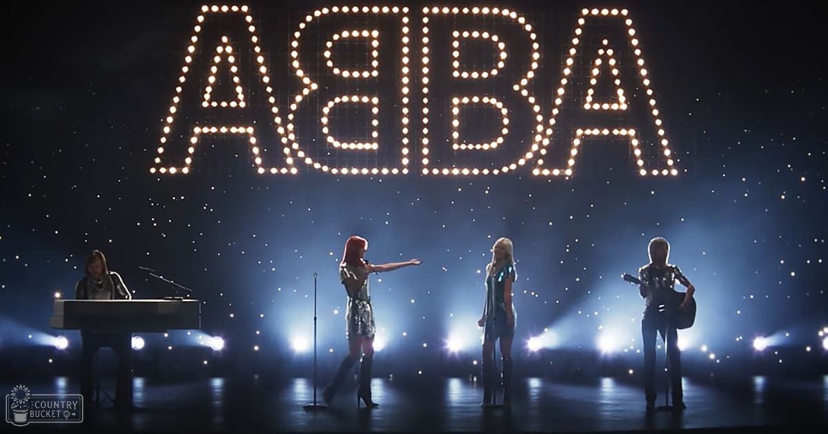 ABBA performance scene with performers in an indoor venue with professional lighting and cosmic ambiance, dark blue and black dominate the setting with bright white and yellow from stage lights creating a striking contrast.