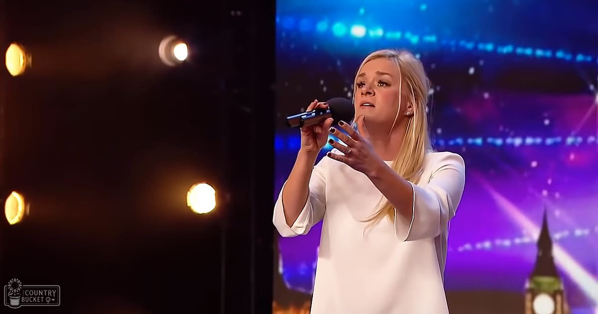 A young adult female performs on a stage under artificial lighting with a cityscape backdrop at night.