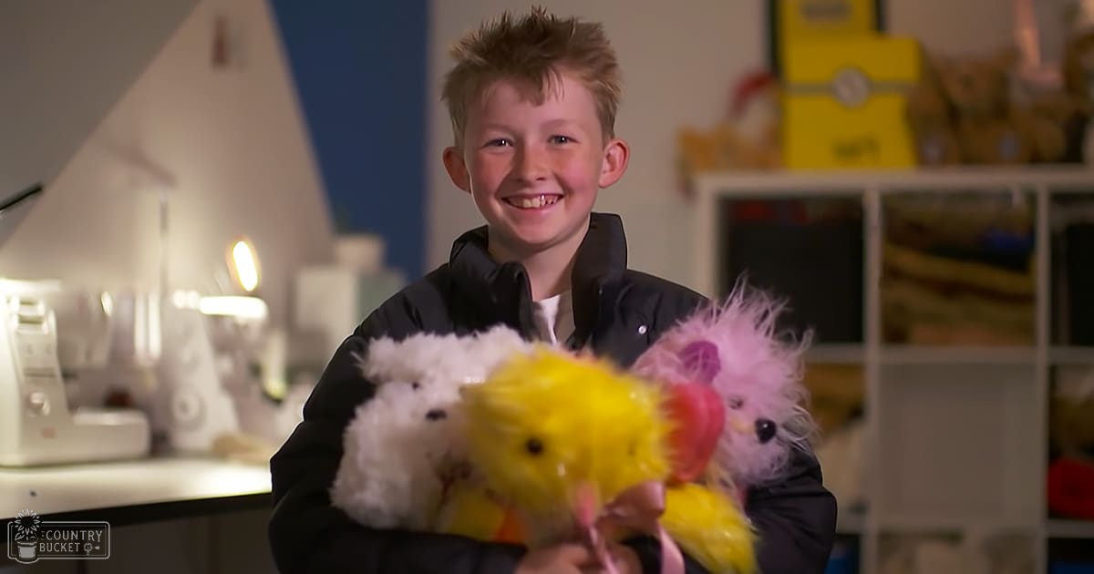 A child wearing a black jacket with relaxed fit and collared long sleeves, standing indoors in front of a white shelf holding various items including a yellow box labeled 'Minions', under artificial lighting at night.