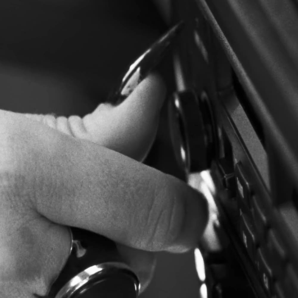 A hand interacting with a keyboard against an indoor background.