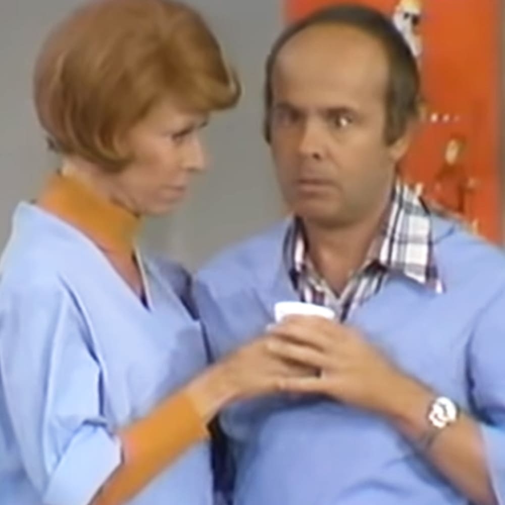 An adult male healthcare professional interacts with a middle-aged to older adult male patient in what appears to be a medical office setting.
