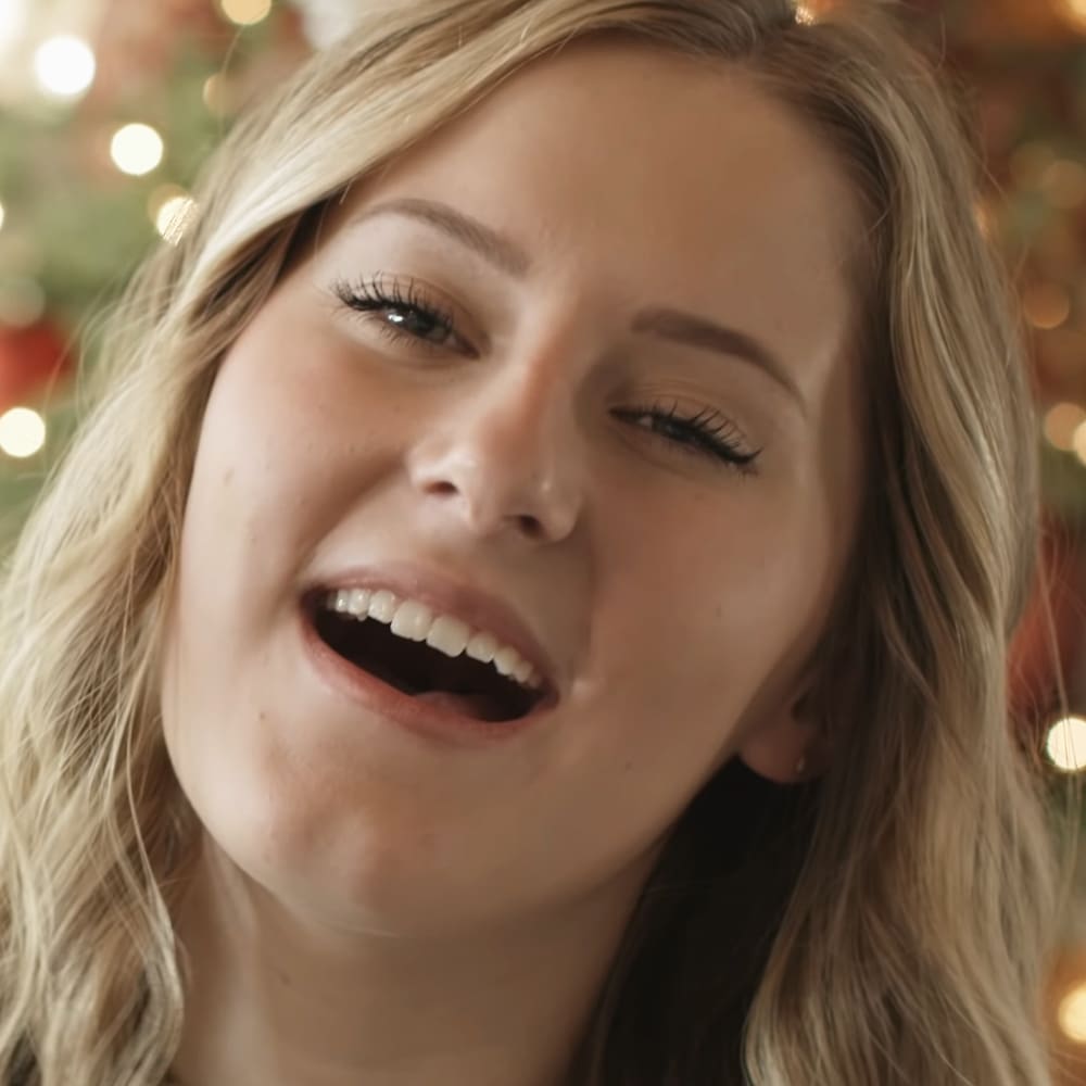 A young adult female wearing dark-colored top indoors during holiday season.