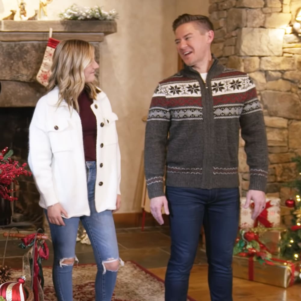 A festive indoor Christmas scene with a couple in a cozy living room adorned with holiday decorations and a decorated Christmas tree.