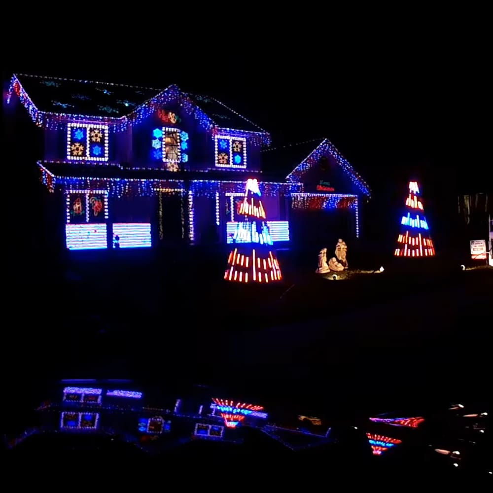 A house adorned with colorful Christmas lights and decorations in an outdoor winter night setting.