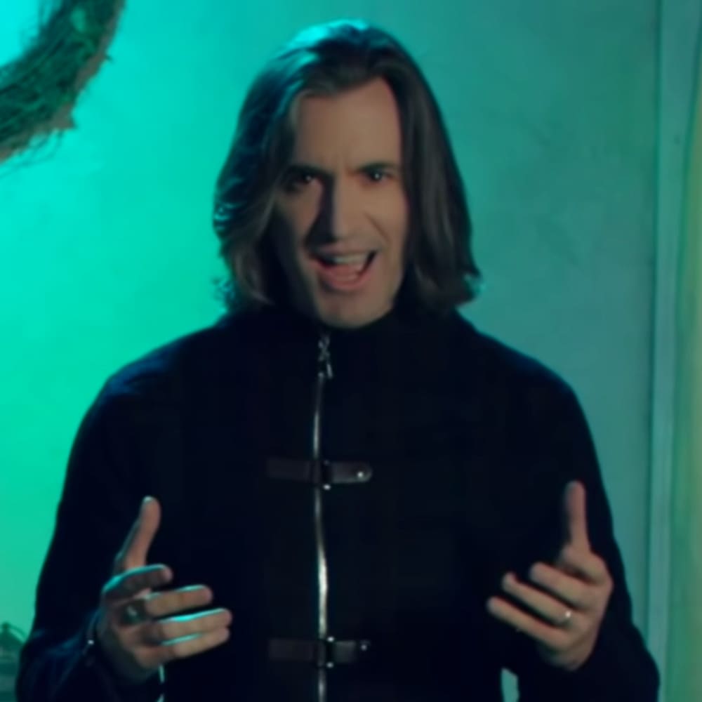 Young adult male wearing a relaxed fit, high-collared, long-sleeved black zip-up jacket with synthetic blend material in an indoor setting.