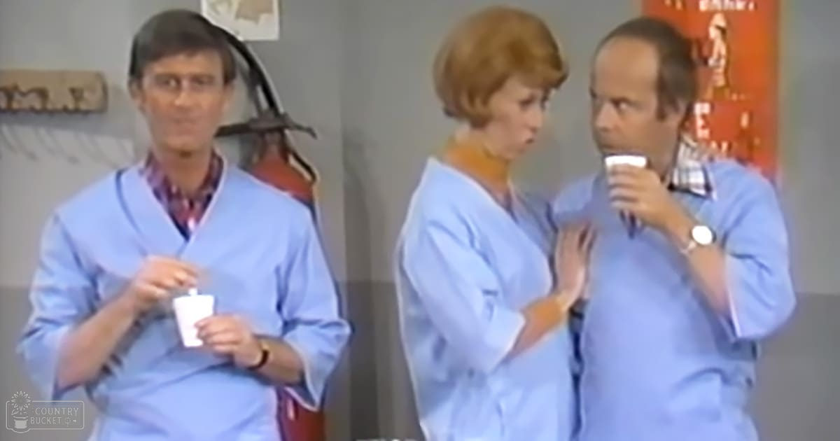 Medical setting with adults wearing light blue scrubs, minimal decor indoors, neutral-colored walls and artificial lighting.