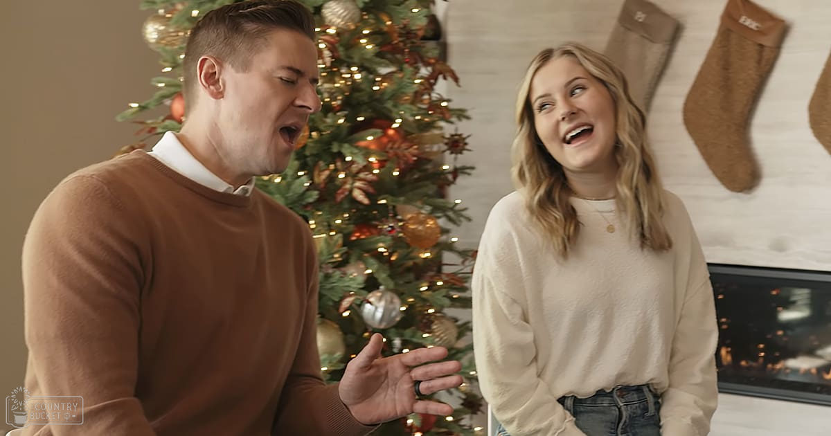 A young couple in front of a decorated Christmas tree, likely at home during winter.