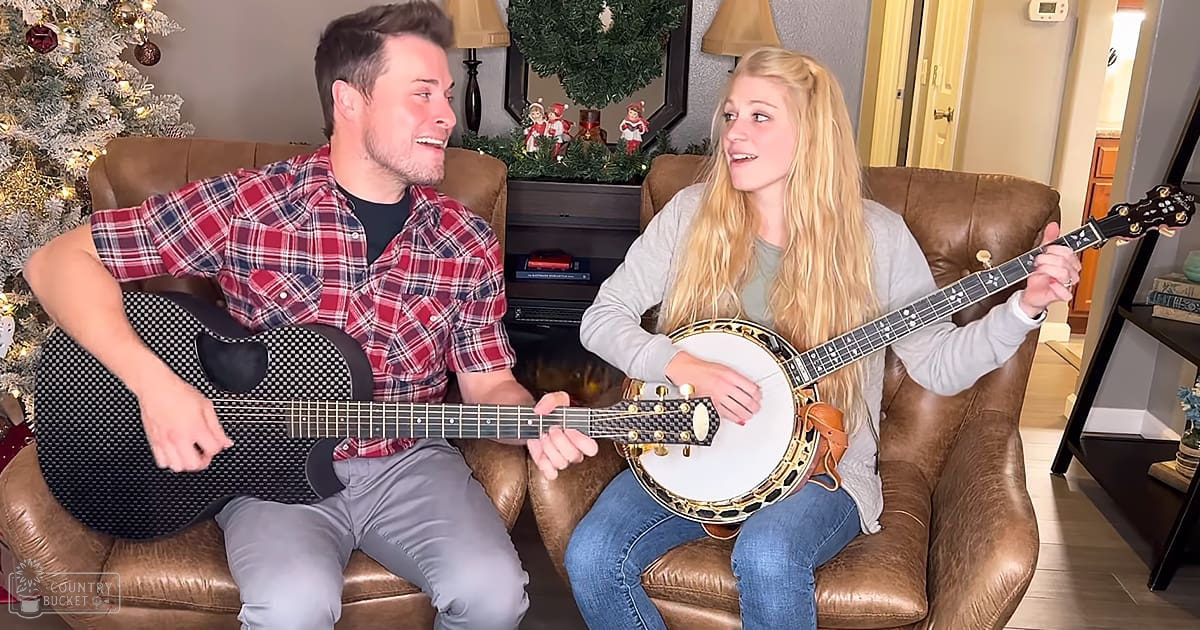 A musical performance in a home setting during Christmas time, with two young adults seated on a brown leather couch with a decorated Christmas tree nearby.