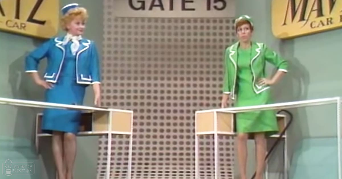 Two individuals in professional uniforms, one in a blue stewardess uniform with white trim and hat, the other in a green dress or suit with white trim and headband, standing on podiums against a backdrop labeled 'GATE 15' in an indoor studio setting.