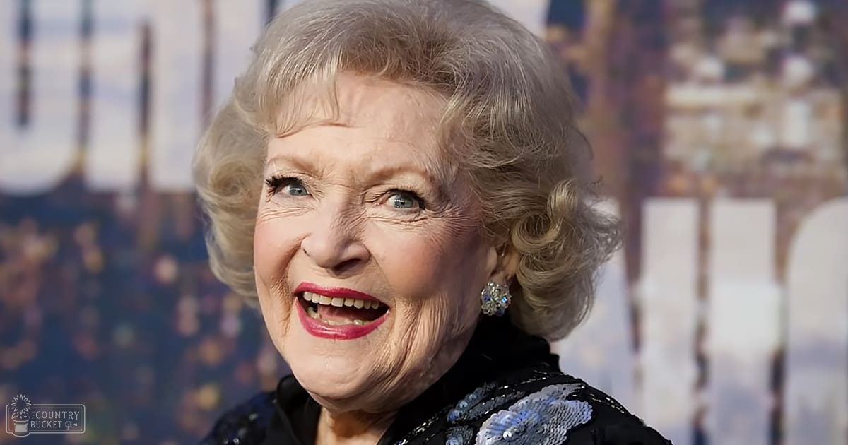 An older adult female wearing a black, form-fitting dress adorned with blue and silver sequins at what appears to be a public event or premiere.