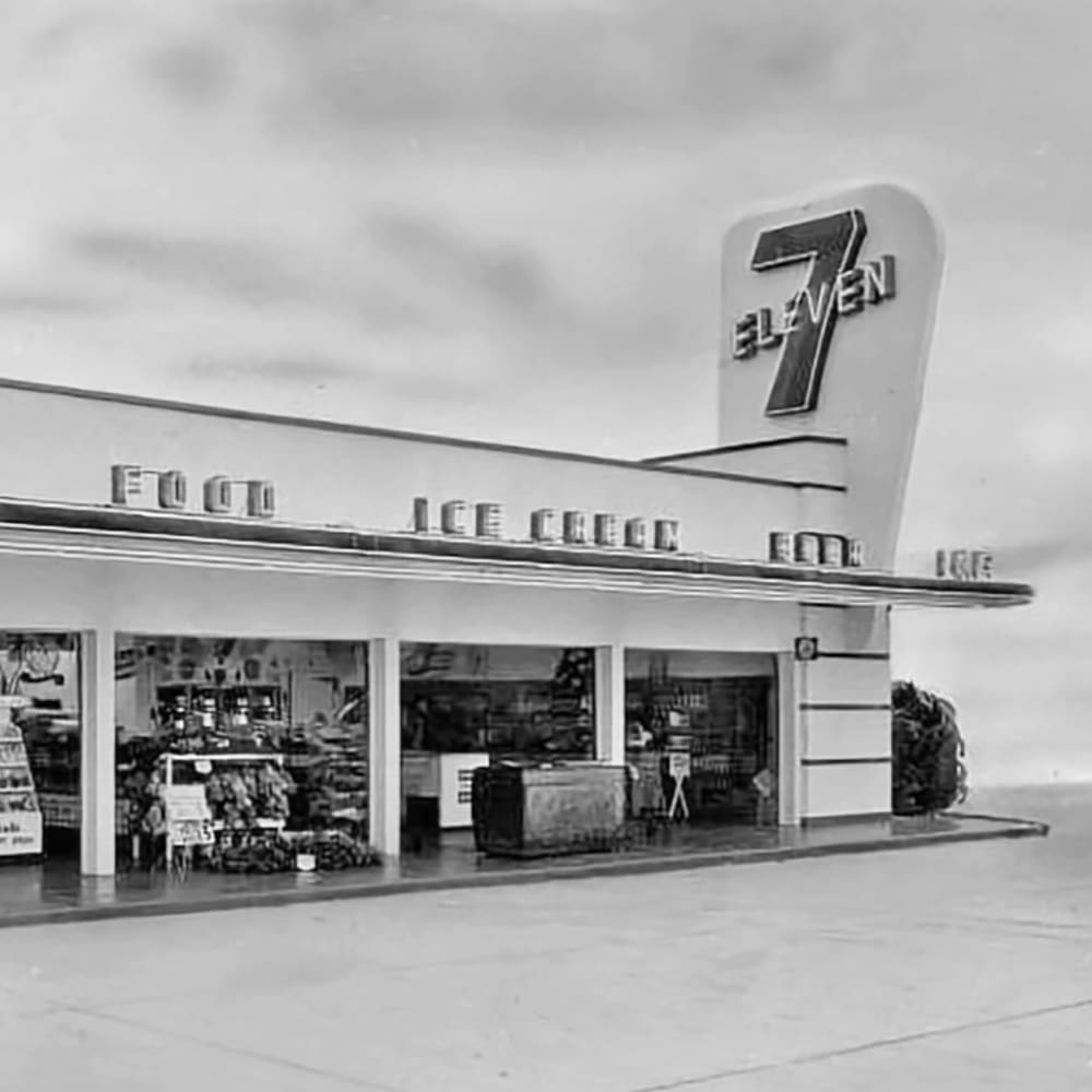 Urban 7-Eleven storefront with decorative elements in an overcast mid-20th-century setting