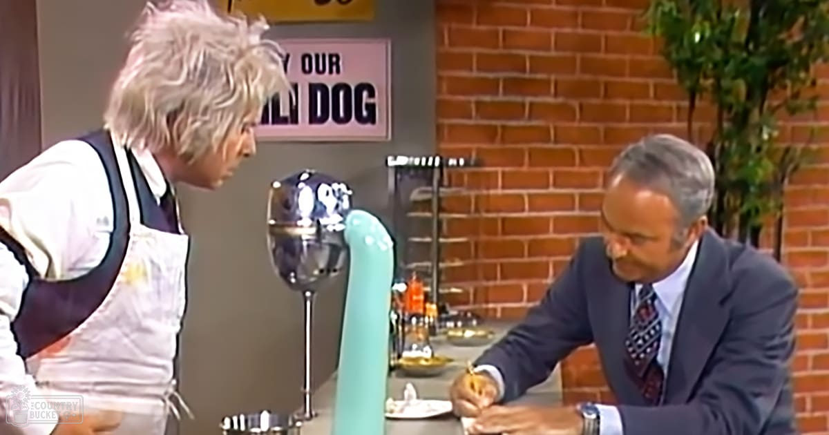 A chef in a dark apron interacts with an older adult male dressed in formal attire, suggesting a professional or social setting. The scene includes kitchen elements like a beer tap and food items on the counter.