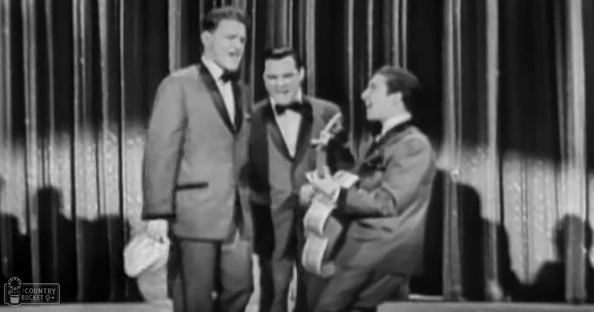 Stage scene with young adult male performers in formal attire, curtains backdrop, likely from a performance or variety show.