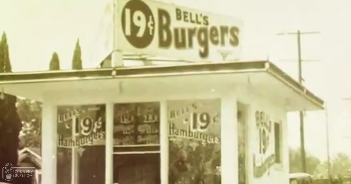 The exterior of Bell's Burgers restaurant in an urban setting displays 19¢ hamburger advertisements against muted tones, possibly sepia or faded beige, suggesting an old photograph.