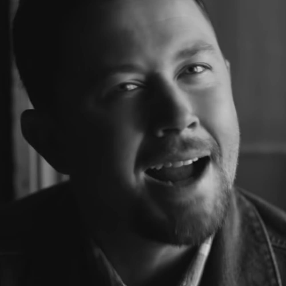 Middle-aged man wearing a dark jacket indoors with soft, even lighting suggesting daytime.