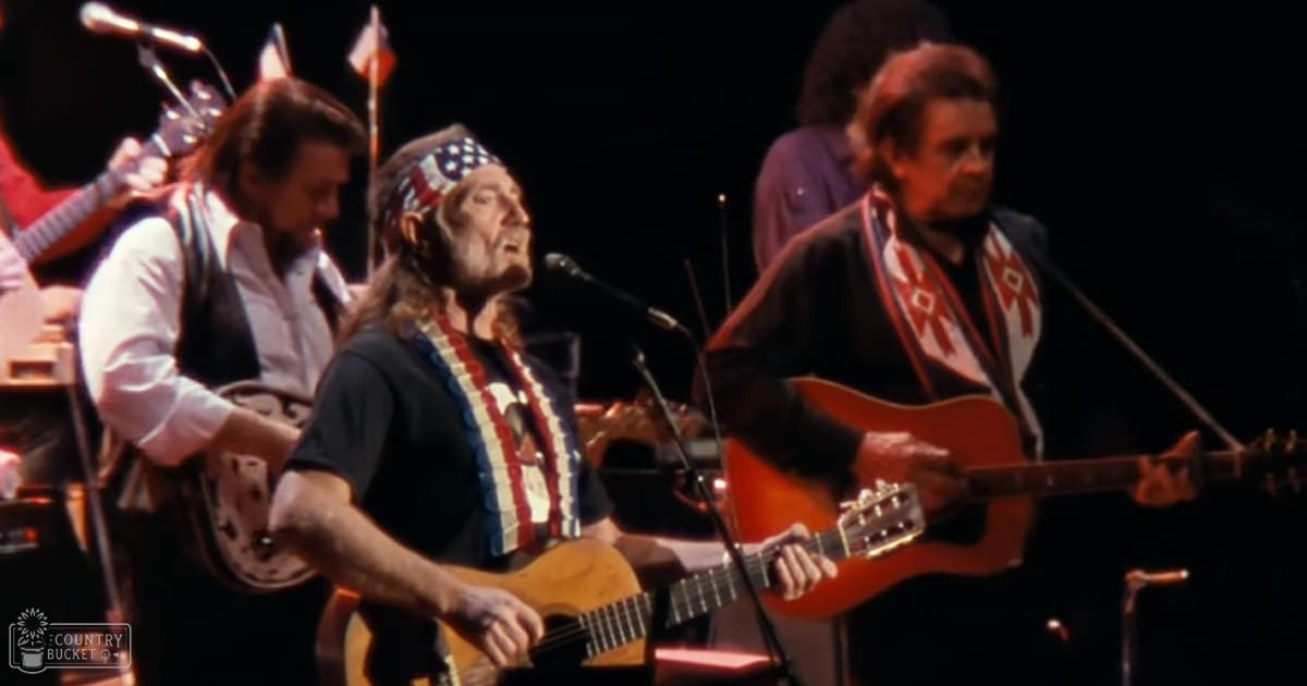 Musical performance with performers wearing American flag-themed accessories, stage setting with dark lighting and stringed instruments.