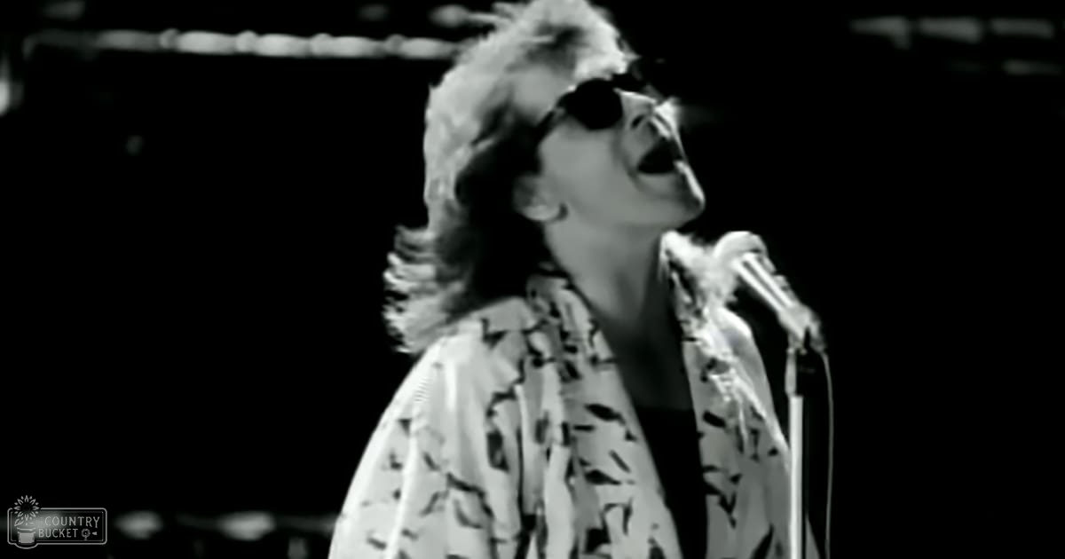 A middle-aged female performer singing into a microphone at what appears to be a concert setting.