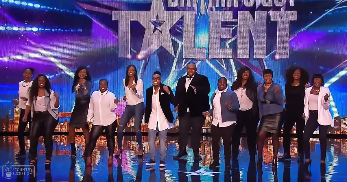 A group of young adult females performing at a talent show on stage; one adult male appears as part of the performance crew.
