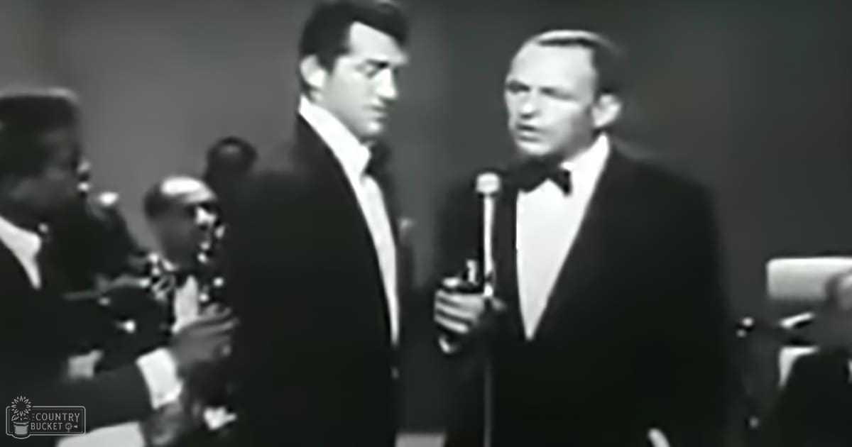 Musical performance with two adult male singers dressed formally in a dimly lit indoor venue, possibly evening or night time.