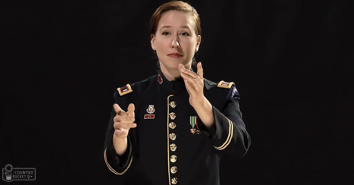 A young adult female in a form-fitting military uniform with medals, set against a black background.