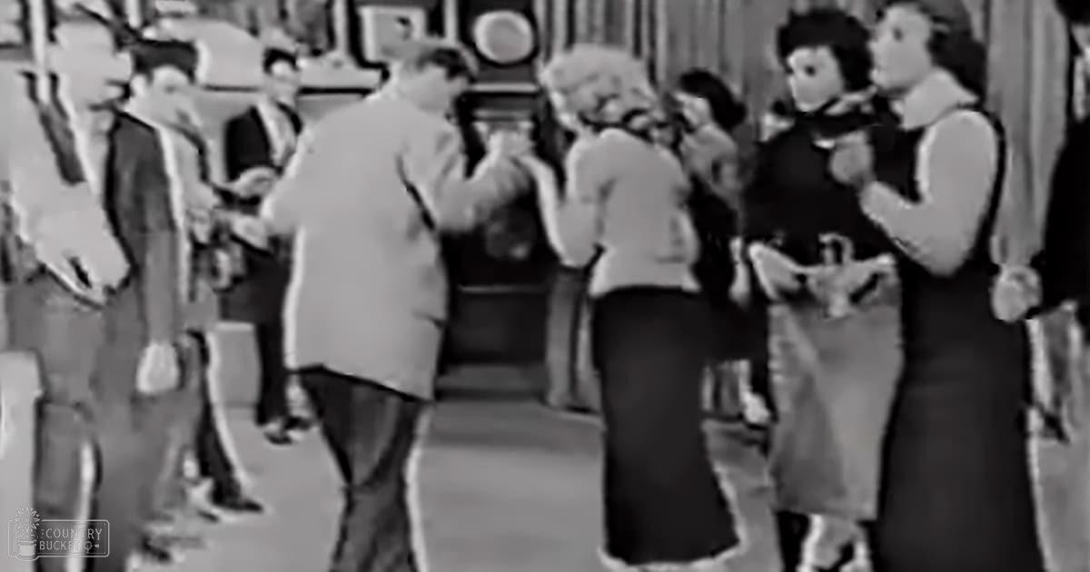 A social gathering in an indoor setting with adults dressed formally typical of the mid-20th century.