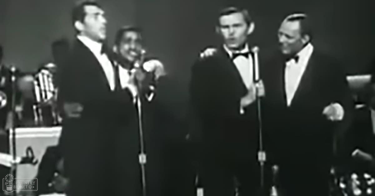 A musical performance scene with four adult males dressed formally on a stage, likely from the mid-20th century.