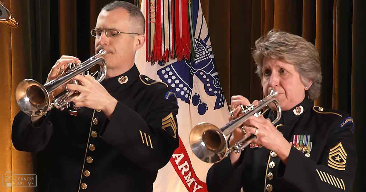 Military band performance indoors under artificial stage lighting at night, dark uniforms with gold accents, wooden paneling, American flag backdrop