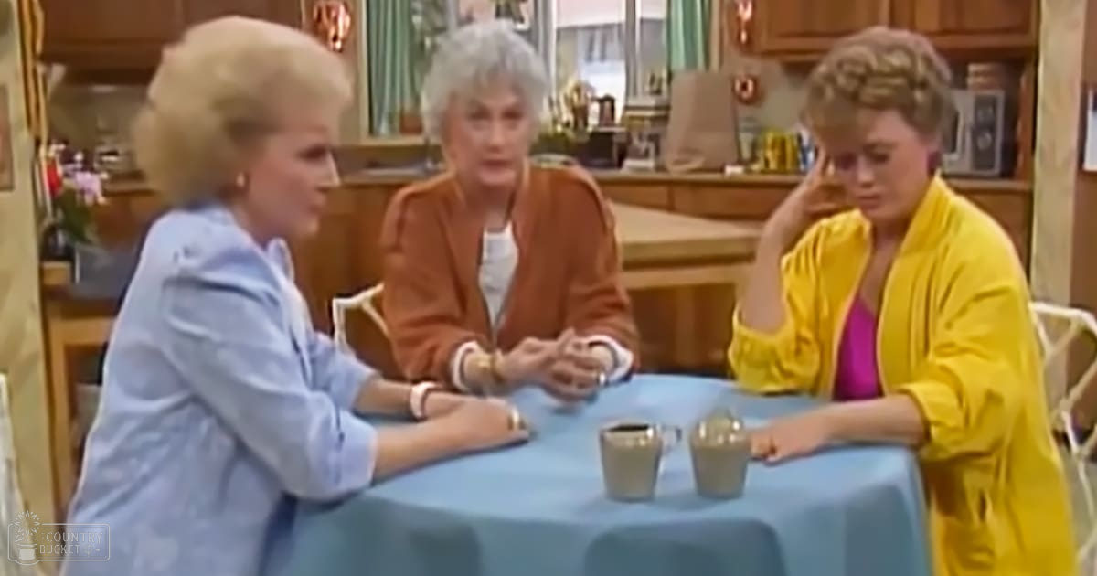 Three women in an indoor setting, possibly a diner or café. One wears a light blue blouse with a wristwatch and bracelet; another sports a brown jacket over white, accessorized similarly; the third dons a bright yellow jacket over pink. Furniture includes wooden chairs and a blue tablecloth.