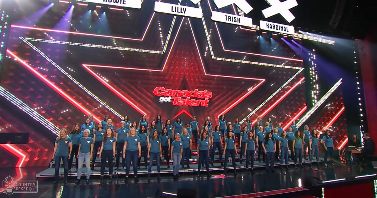 A group performance at 'Canada's Got Talent' in a studio setting with young adult female performers wearing blue t-shirts and dark jeans, bright stage lights with red and white stars.