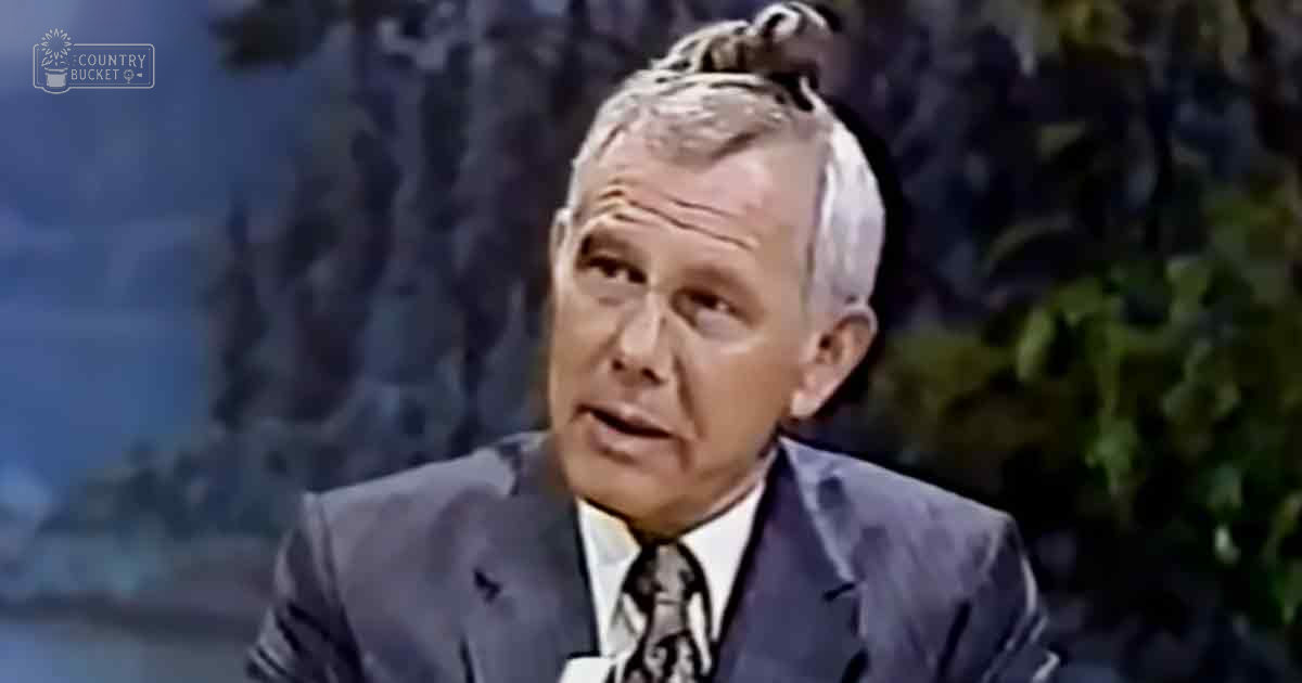 Older adult male in a professional setting with a backdrop of mountains and greenery.