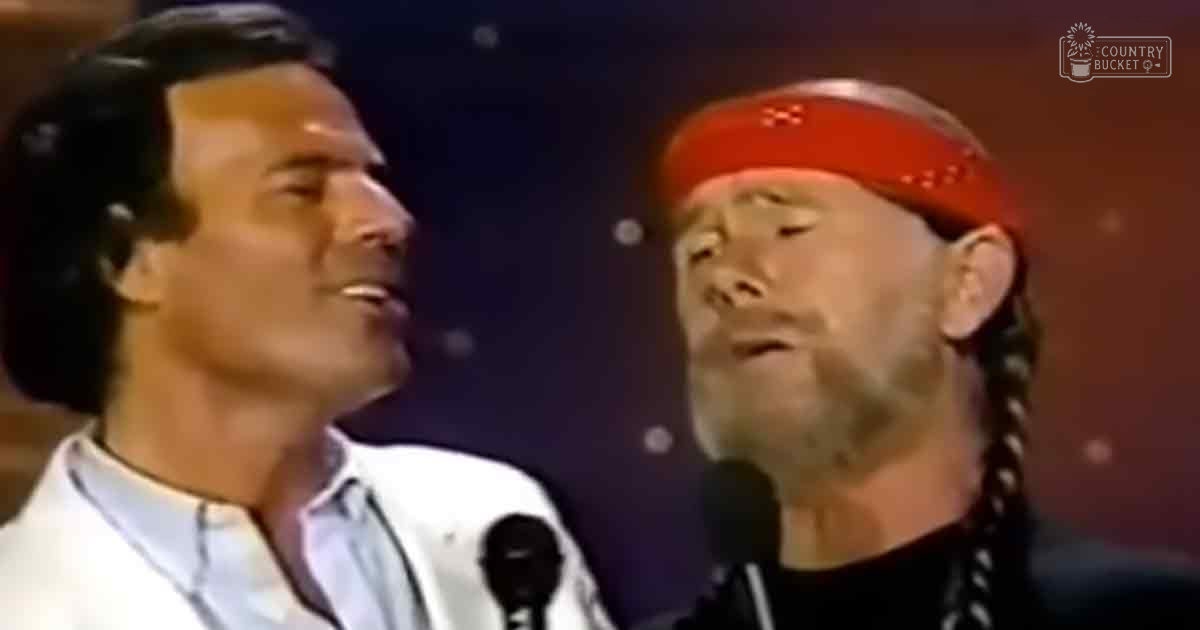 Musical performance scene with two adult males on stage, one in a white shirt and another wearing black with a red bandana, under dark stage lighting.